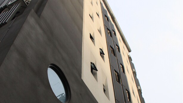 A tall building with a modern architectural design, featuring multiple balconies and circular windows. - Century Hotel (Kaohsiung)