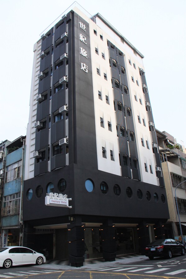 Un hotel de varios pisos con fachada moderna, destacándose una entrada principal y un letrero que indica que es el Century Hotel.