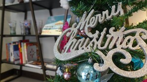 A Christmas tree with a 'Merry Christmas' ornament and a book shelf in the background. - Century Hotel (Kaohsiung)