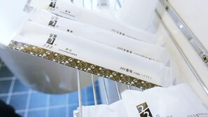 A rack of white toothbrushes with gold and black branding. - Century Hotel (Kaohsiung)
