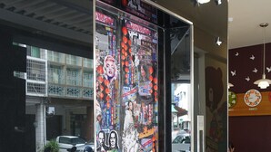 A modern building entrance with a glass door adorned with various stickers and decals. - Century Hotel (Kaohsiung)