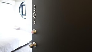 A hotel room with a bed, a door with numbers, and a window. - Century Hotel (Kaohsiung)