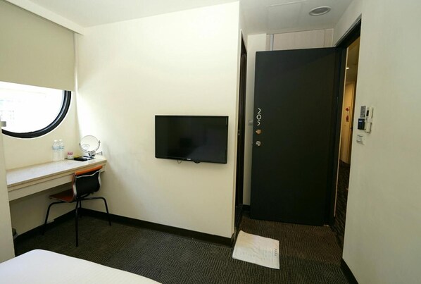 A hotel room with a bed, a desk with a computer, a television, and a door with a number. - Century Hotel (Kaohsiung)