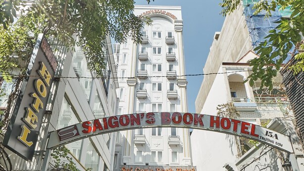 The entrance to Saigon's Book Hotel with a clear pathway leading to the entrance, surrounded by greenery and modern buildings.