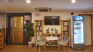 A cozy library area with bookshelves, a television, a Panasonic refrigerator, and a small table with chairs.