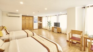 A hotel room with two beds, a TV, a desk, and a chair.