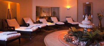 Un espacio de spa con varias sillas reclinables, una fuente decorativa y un espejo.