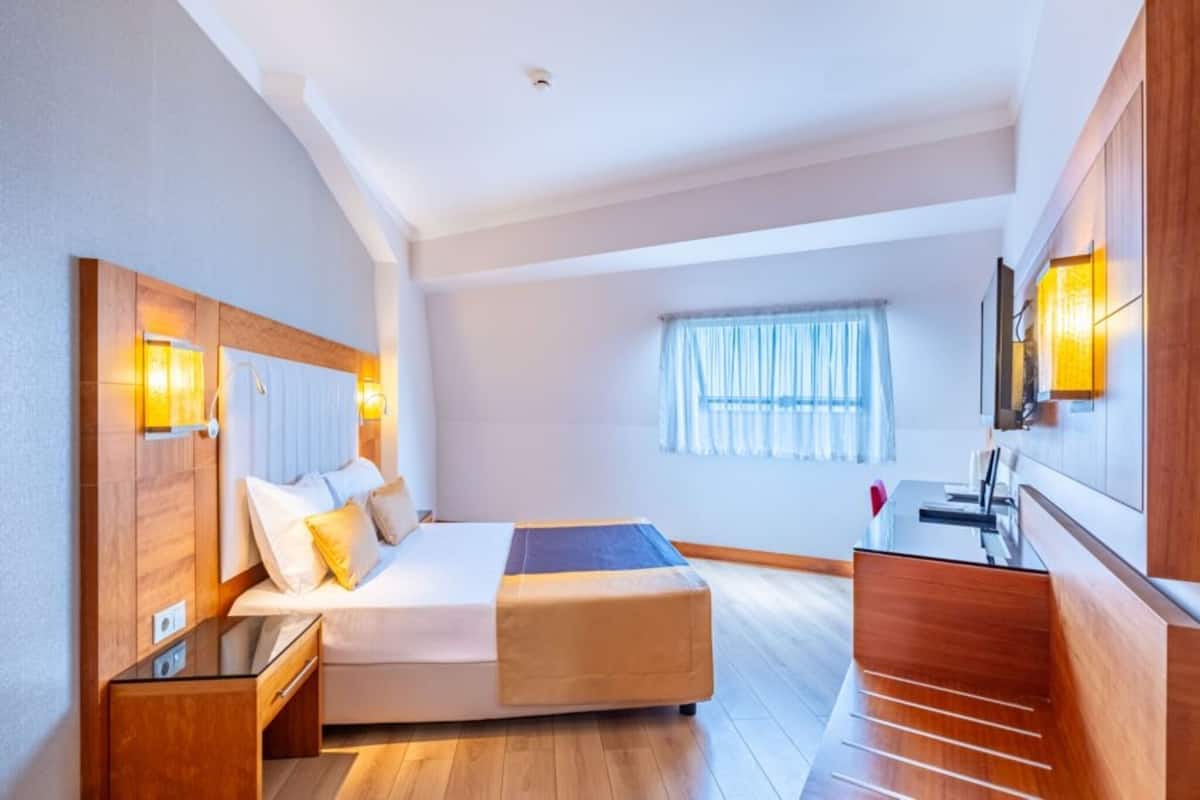 A modern hotel room with a bed, bedside table, and a desk area.