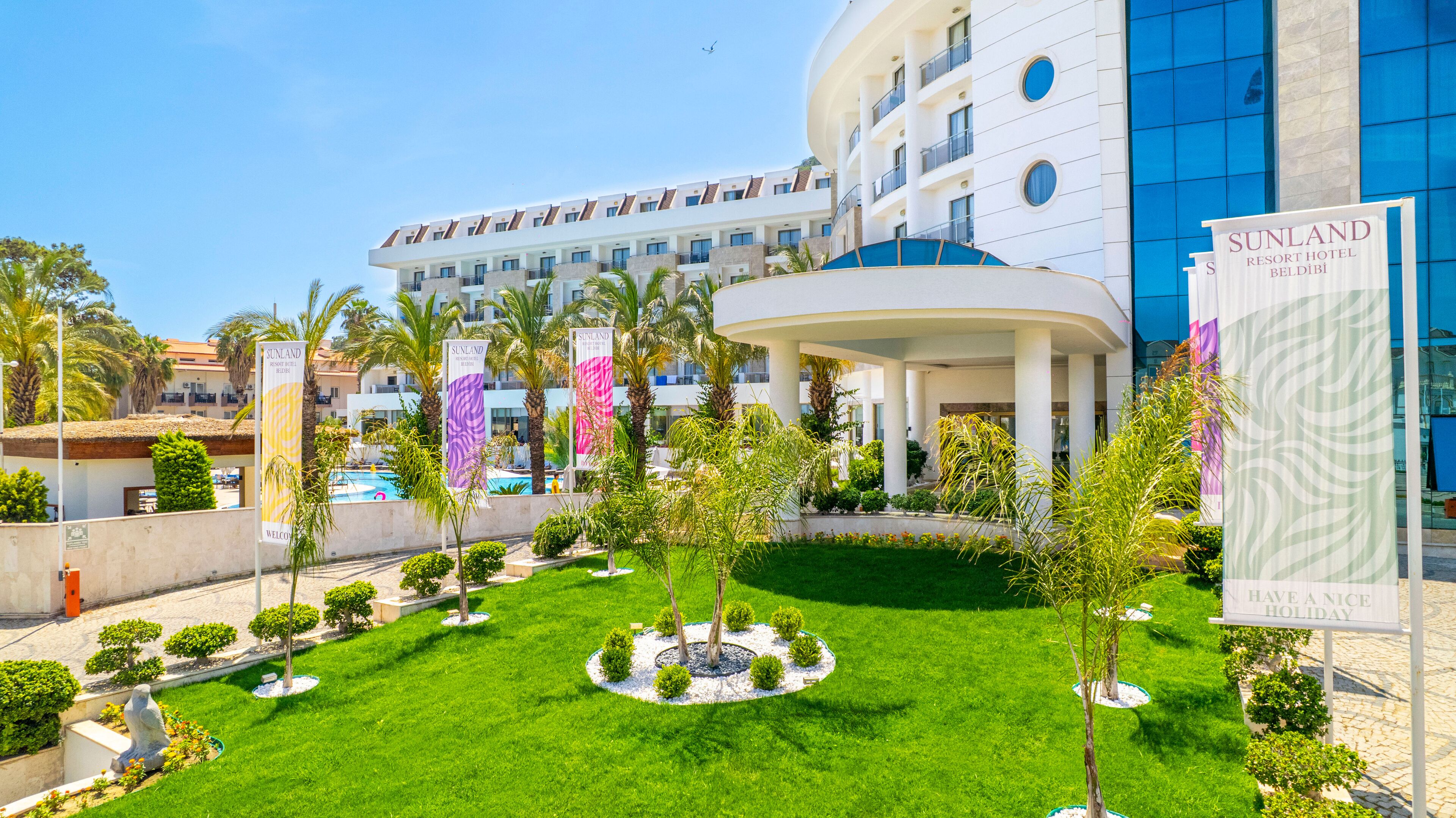 Un hôtel de villégiature doté d’une piscine, de palmiers et d’une pelouse bien entretenue.