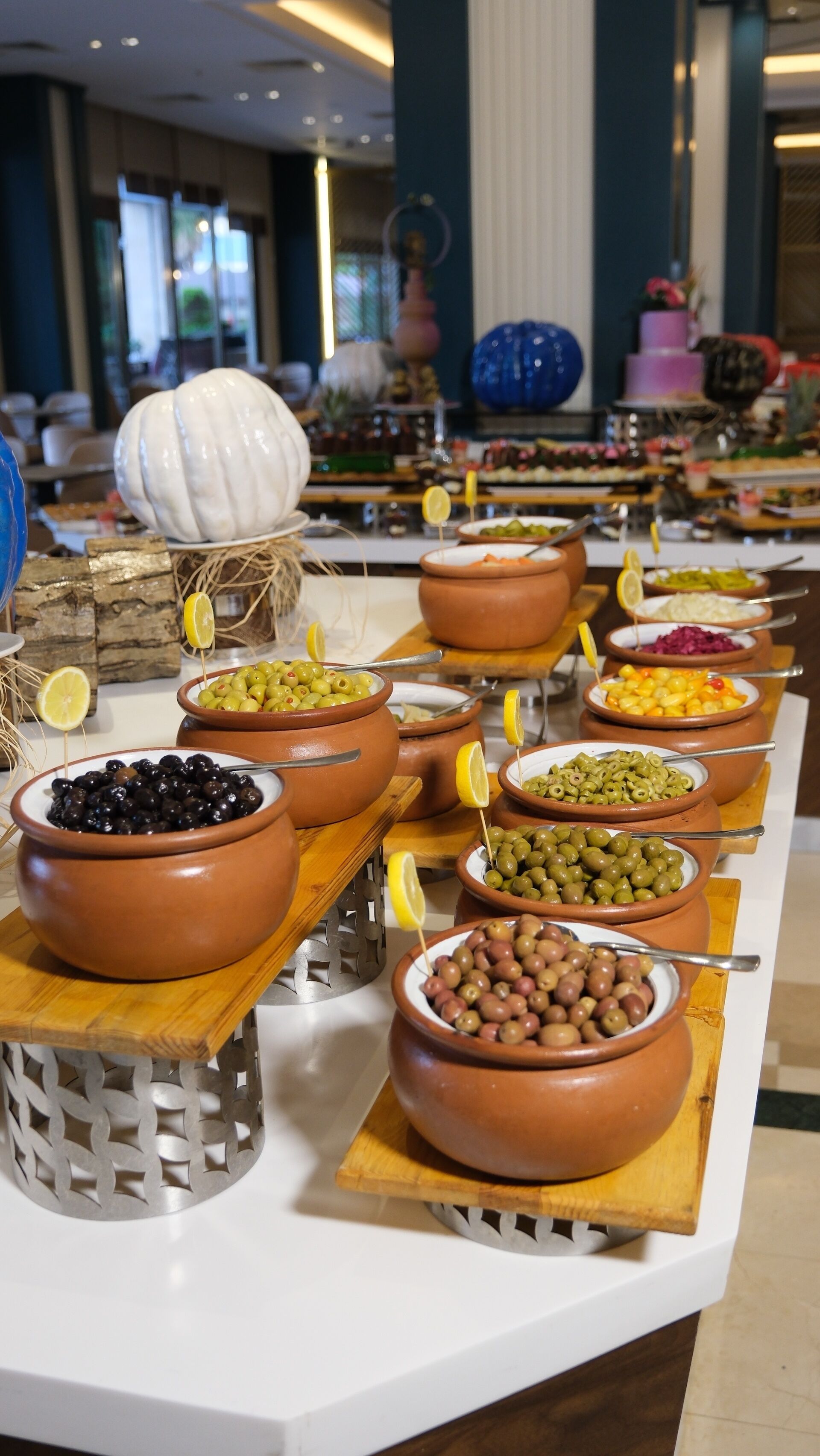 A buffet with various dishes in terracotta bowls, some with lemon slices.