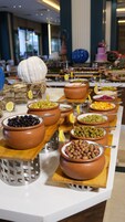 Un bufé con diversos platos servidos en cuencos de terracota, algunos con rodajas de limón.