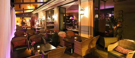 An indoor seating area with wicker furniture, a bar, and a view of the cityscape.