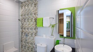 Un baño moderno con ducha, inodoro, lavamanos y un espejo con marco verde.