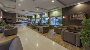 A hotel lobby with sofas, a reception desk, and a large window. - Hotel Asdem Park (Kemer)