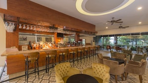 A bar area with a long counter, multiple chairs, and a ceiling fan. - Hotel Asdem Park (Kemer)