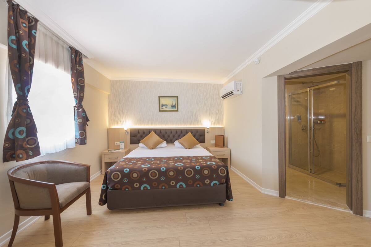 Une chambre d’hôtel équipée d’un lit, d’une chaise, d’une table de chevet, d’un climatiseur et d’une douche.