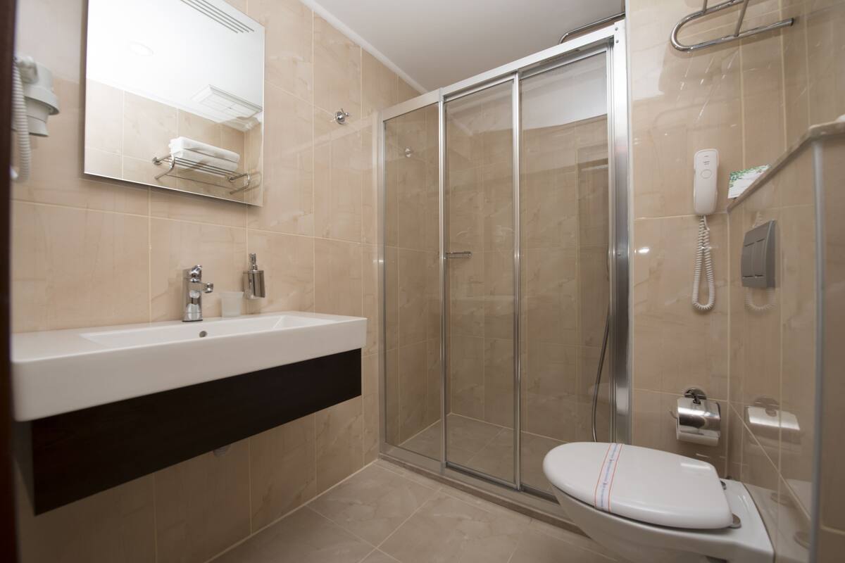 Une salle de bain moderne avec un grand lavabo, une douche à parois de verre et des toilettes.