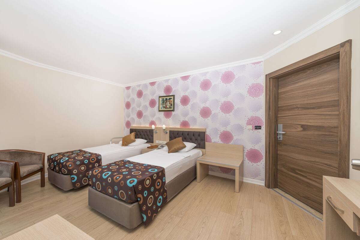 Une chambre d’hôtel avec deux lits, un bureau, une chaise et une porte en bois.