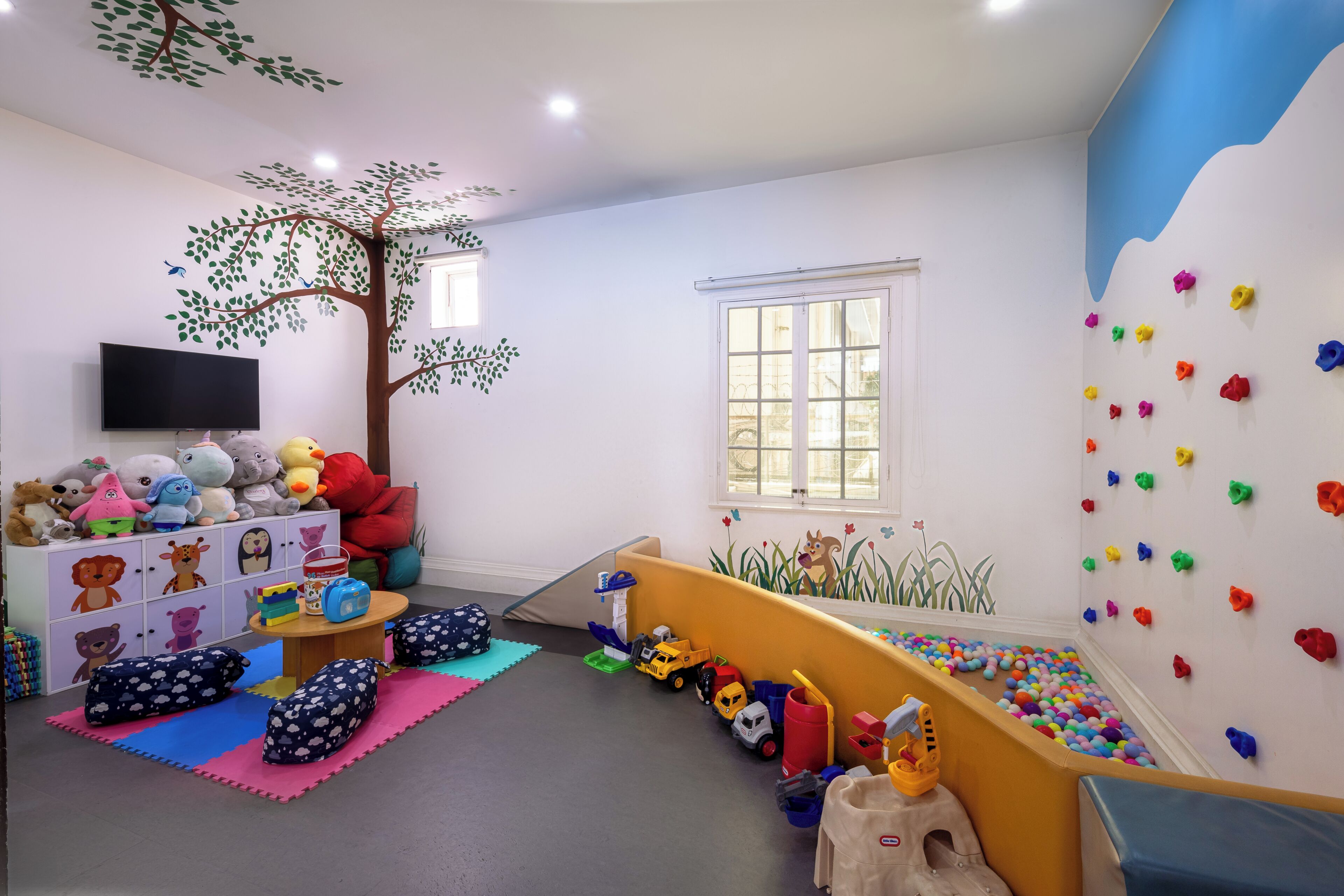 A child's playroom with a climbing wall, toys, and a TV.