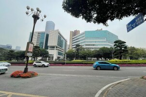 A city intersection with modern buildings, a traffic light, and a blue car.