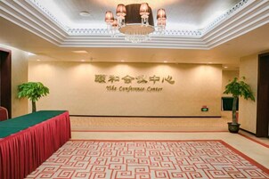 A conference room with a patterned carpet, a green table, and a chandelier.