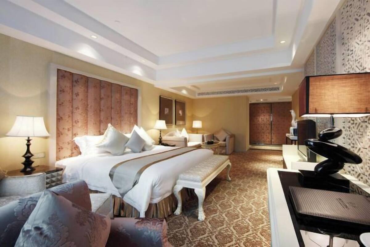 A hotel room with a large bed, a desk, a chair, and a sofa.