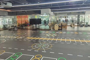 Un espacio interior amplio con equipo de ejercicio, una pantalla grande y un suelo con diseño.