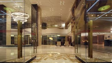 A spacious lobby with a high ceiling, glass walls, and a central chandelier.