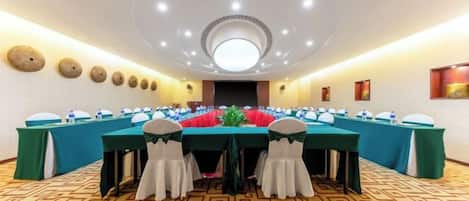 A conference room with a long table, multiple chairs, and a patterned carpet.