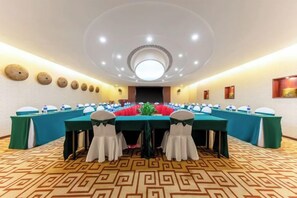 Une salle de conférence avec une longue table, de nombreuses chaises et un tapis à motifs.