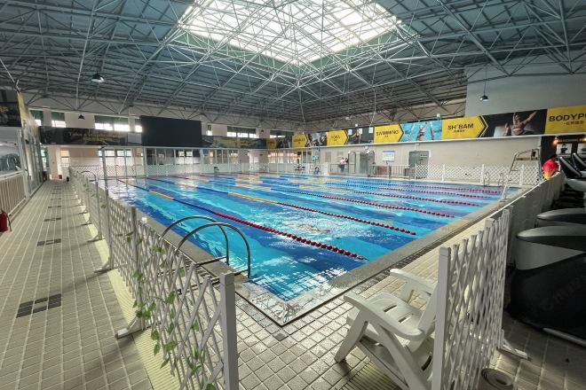 Una piscina interior con carriles, techo alto y suelo de baldosas.