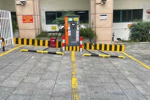 A parking area with a fuel pump, yellow and black safety barriers, and a gated entrance. - Zhongshan Yihe Junli Hotel (Holiday Plaza Branch) (Zhongshan)