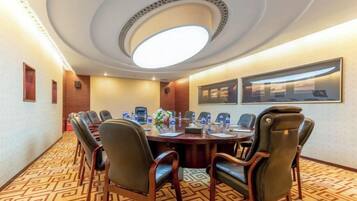 A conference room with a long table, chairs, a ceiling light, and framed pictures on the wall.