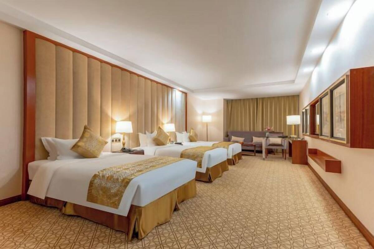 A hotel room with three beds, a desk, and a chair.
