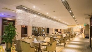 A hotel lobby with a long reception desk, multiple seating areas with chairs and tables, and a decorative hanging light fixture. - Zhongshan Yihe Junli Hotel (Holiday Plaza Branch) (Zhongshan)