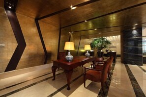 A lobby with a reception desk, chairs, and a potted plant. - Zhongshan Yihe Junli Hotel (Holiday Plaza Branch) (Zhongshan)