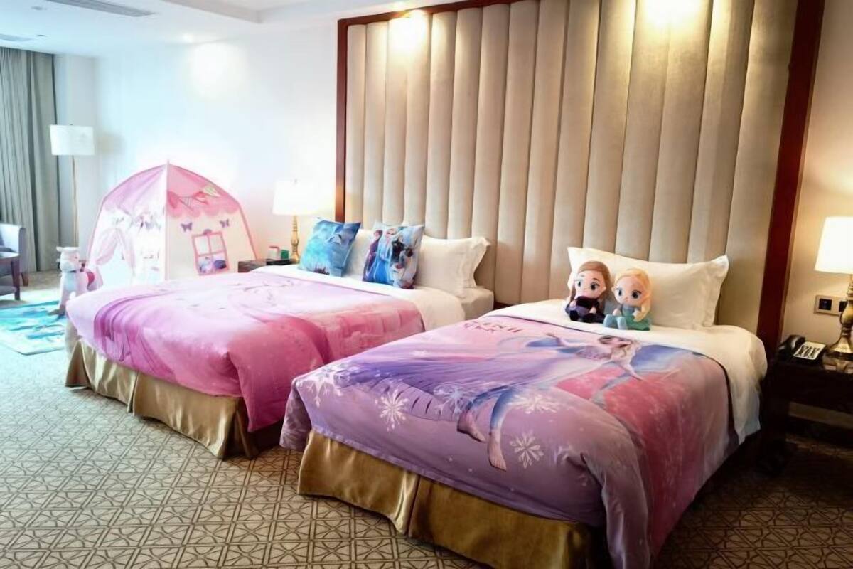 A hotel room with two beds, a headboard, a nightstand, and a small tent-like structure.
