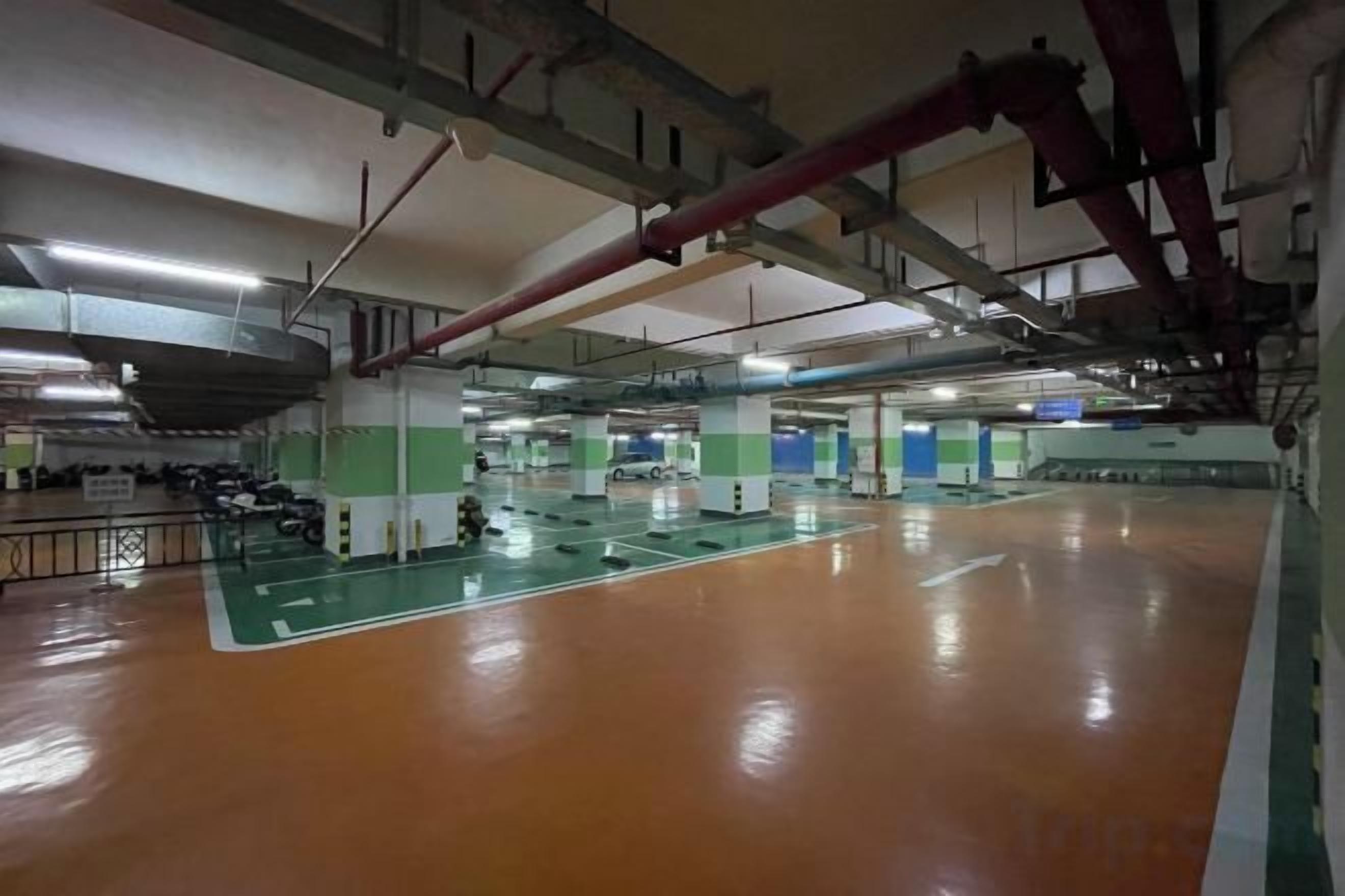 An indoor sports hall with a basketball court, seating areas, and visible structural elements like beams and pipes.