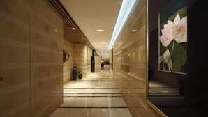 A hallway with reflective marble flooring, a modern ceiling design, and a large floral artwork on the right wall. - Zhongshan Yihe Junli Hotel (Holiday Plaza Branch) (Zhongshan)