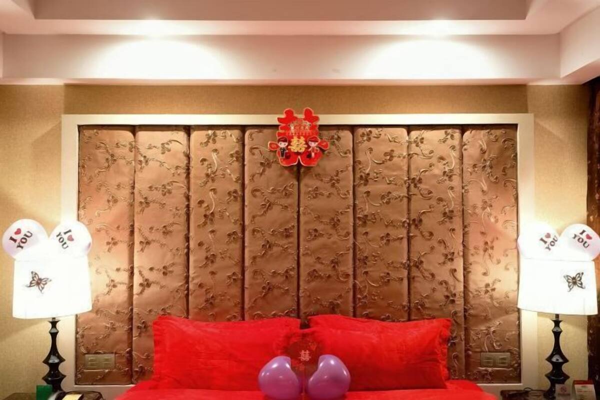A hotel room with a large bed, two bedside lamps, and a decorative headboard.