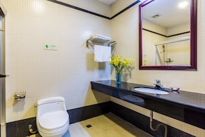 A modern bathroom with a white toilet, a sink with a mirror above it, and a towel rack. - Kangyi Hotel (Foshan)