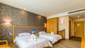Une chambre d’hôtel avec deux lits, un petit bureau, une chaise et un mur décoratif.
