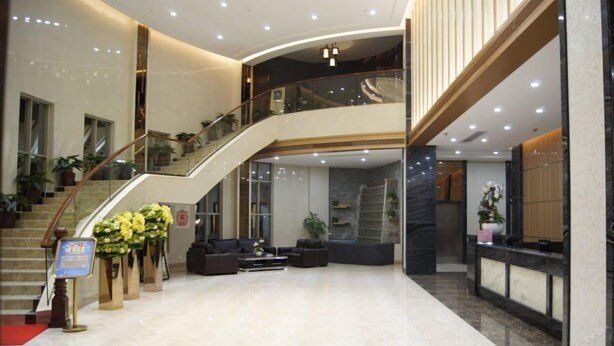 Un hall d’entrée spacieux avec un escalier en colimaçon, un coin salon et un comptoir d’accueil.
