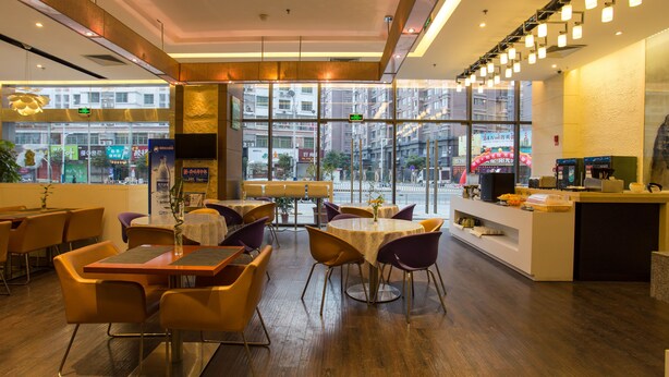 Un intérieur de restaurant moderne avec un plancher en bois, des tables rondes et des chaises violettes.