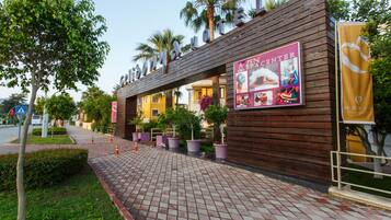 A hotel with a wooden facade, a Zen Center sign, and potted plants along the walkway.
