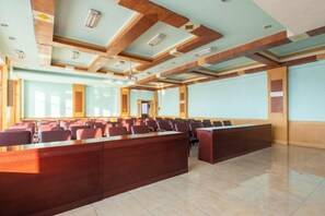 Un salón de conferencias con una larga mesa, sillas y una pantalla para proyector.