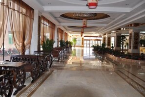 A hotel lobby with a long corridor, wooden furniture, and potted plants. - Beizhen Hotel (Beizhen)