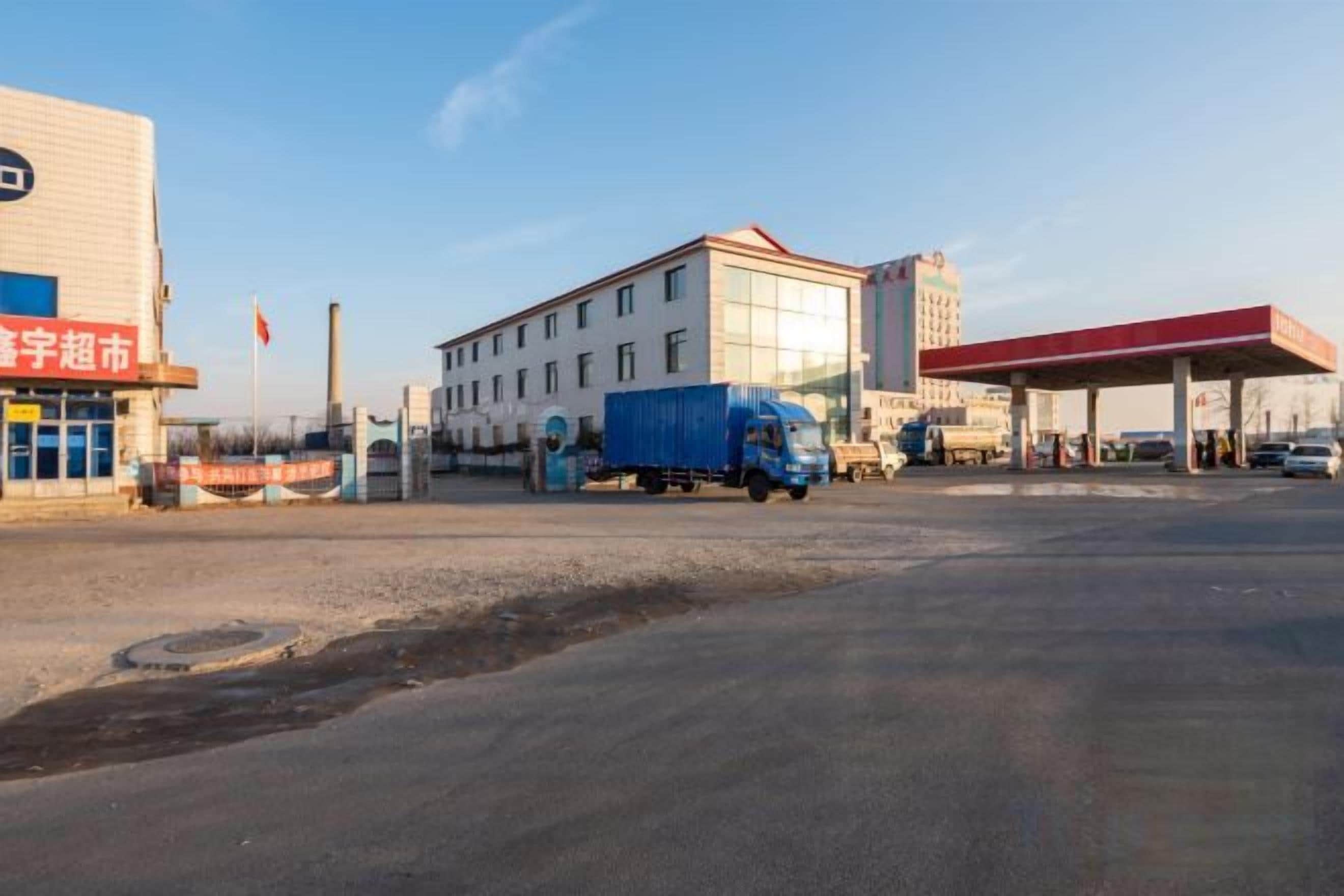 Un edificio con techo rojo y una camioneta azul estacionada al frente.
