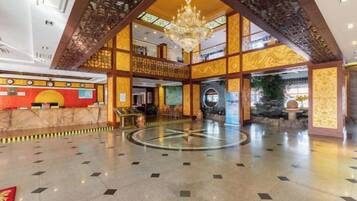 A spacious lobby with a high ceiling, a central chandelier, and a reception desk.
