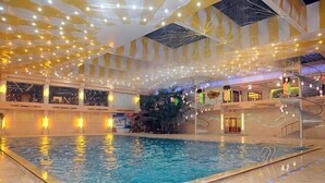 An indoor swimming pool with a central fountain, surrounded by multiple levels of balconies and a staircase. - Beizhen Hotel (Beizhen)